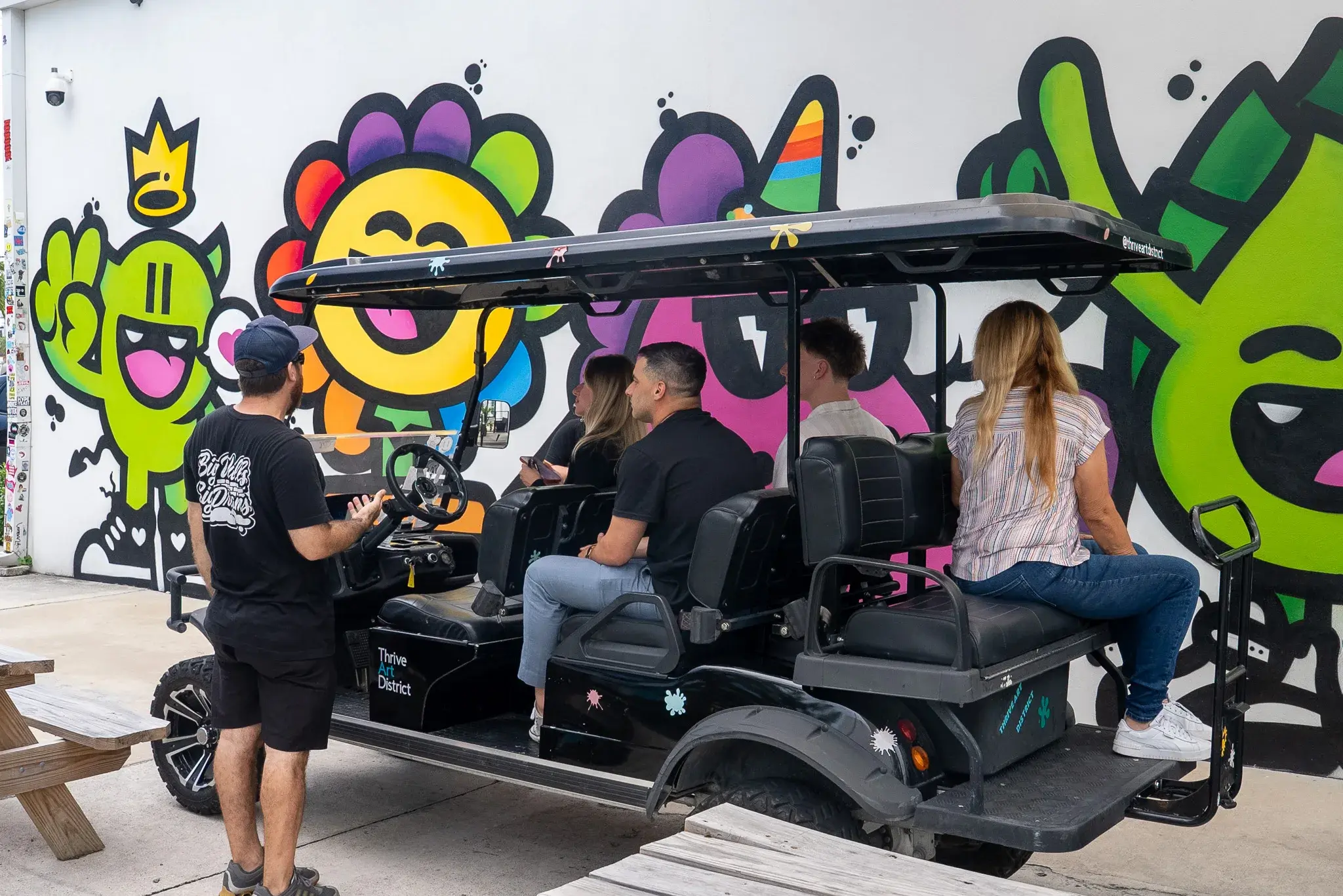 Open air buggy parked beside a colorful Thrive District mural