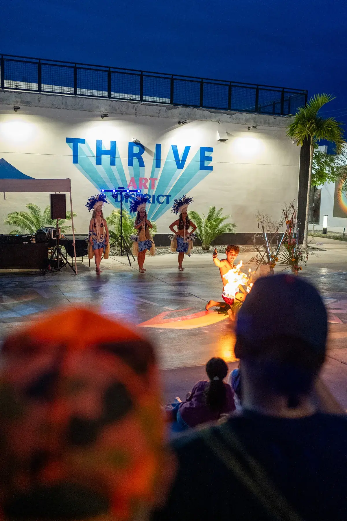 Evening performance watched by a crowd at Thrive District