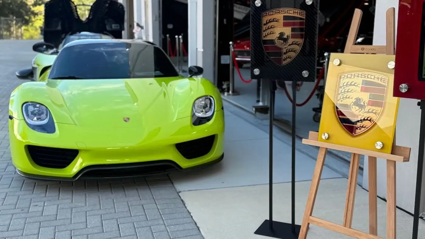 Porsche glass artwork displayed beside a green sports car by Dyer Design Glassworks